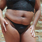 Person wearing black lingerie against a brick wall